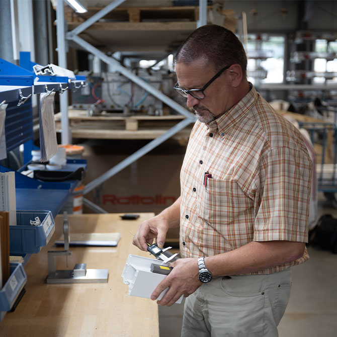 Mitarbeiter kontrolliert mit einer Schieblehre die Maße eines Kunststoffprofils